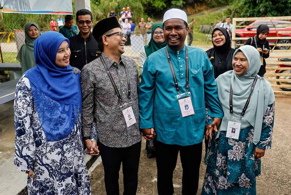 Mohd Azmawi Fikri (dua dari kiri) bersama Mohd Rizwadi (dua dari kanan) beramah mesra selepas mengundi pada PRK Nenggiri di pusat mengundi Tabika Sri Bakawali, Bertama Lama. Foto Bernama