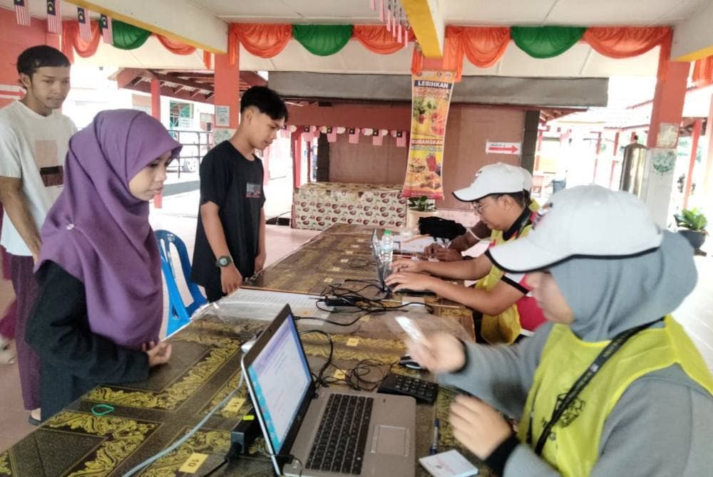 Hafiz Hakimi (berdiri, kanan) antara yang terawal tiba di Pusat Mengundi Sekolah Kebangsaan Jeram Tekoh pada Sabtu.