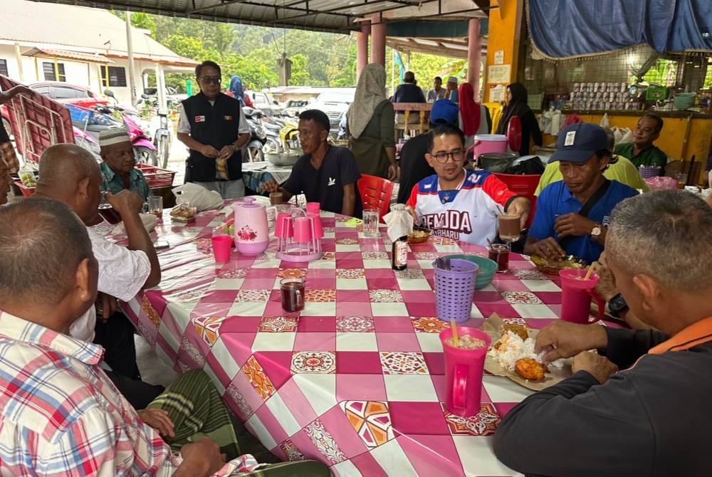 Mohd Azmawi (tiga dari kanan) yang makan bersama penduduk di Sungai Asap A, di sini, pada Ahad.