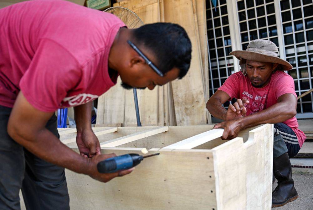 Anuar Abdullah (kanan) bersama Maridwan melakukan kerja-kerja pemasangan keranda. Foto Bernama