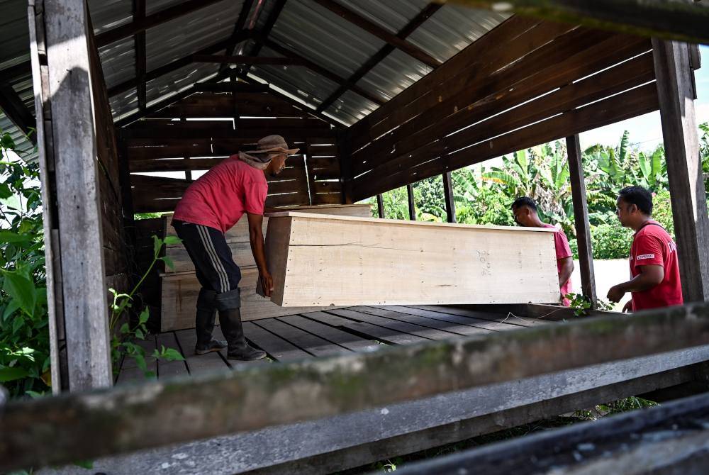Anuar Abdullah (kiri) menyusun keranda yang telah siap dipasang. Foto Bernama