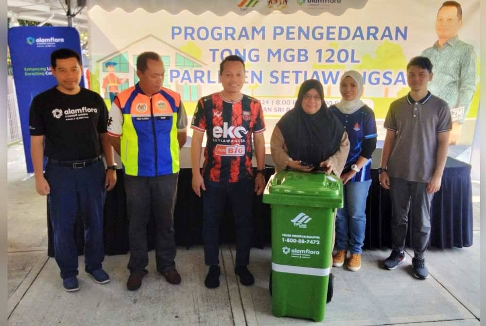 Nik Nazmi (tiga kiri) menyerahkan tong MGB kepada salah seorang penduduk di Taman Sri Rampai di sini.