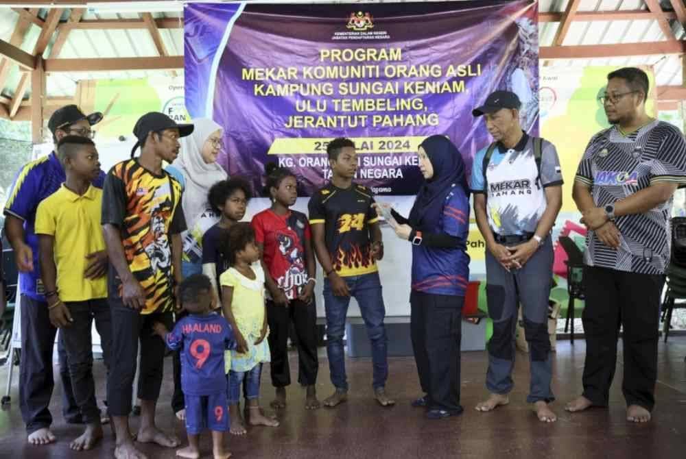 Sarinah (tiga, kanan) beramah mesra dengan sebahagian Orang Asli suku kaum Bateq ketika menyerahkan sijil kelahiran mereka pada Program Mekar Komuniti di Kampung Sungai Keniam, Ulu Tembeling baru-baru ini. Foto Bernama