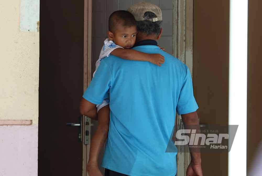Rosli menggendong anak bongsunya semasa menunggu proses bedah siasat di Hospital Sungai Siput pada Ahad.