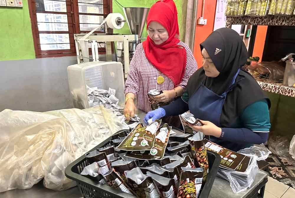 Norini (kiri) dibantu pekerjanya membungkus kopi uncang.