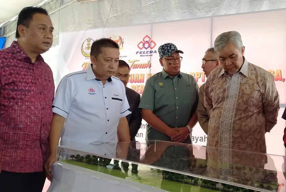 Ahmad Zahid (kanan) mendengar taklimat mengenai Projek Perumahan Rakyat selepas menyempurnakan Majlis Pecah Tanah Projek Pemajuan Kawasan RPT Simpang Tiga di sini pada Isnin.