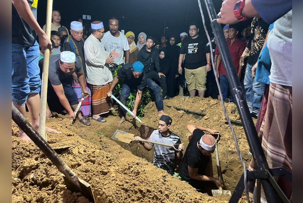 Mohd Yusof (dua dari kanan) turun ke liang lahat bagi mengebumikan arwah Istiqomah.