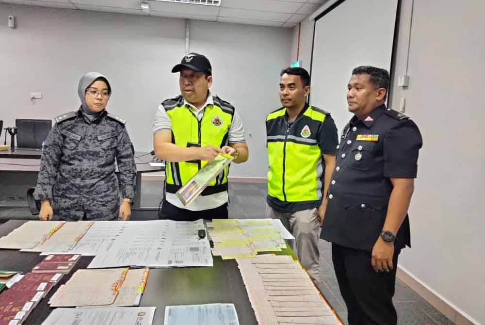 Basri (dua dari kiri) menunjukkan dokumen tamat tempoh yang dirampas dalam serbuan di sebuah kilang besi di Kuala Krai pada Selasa.