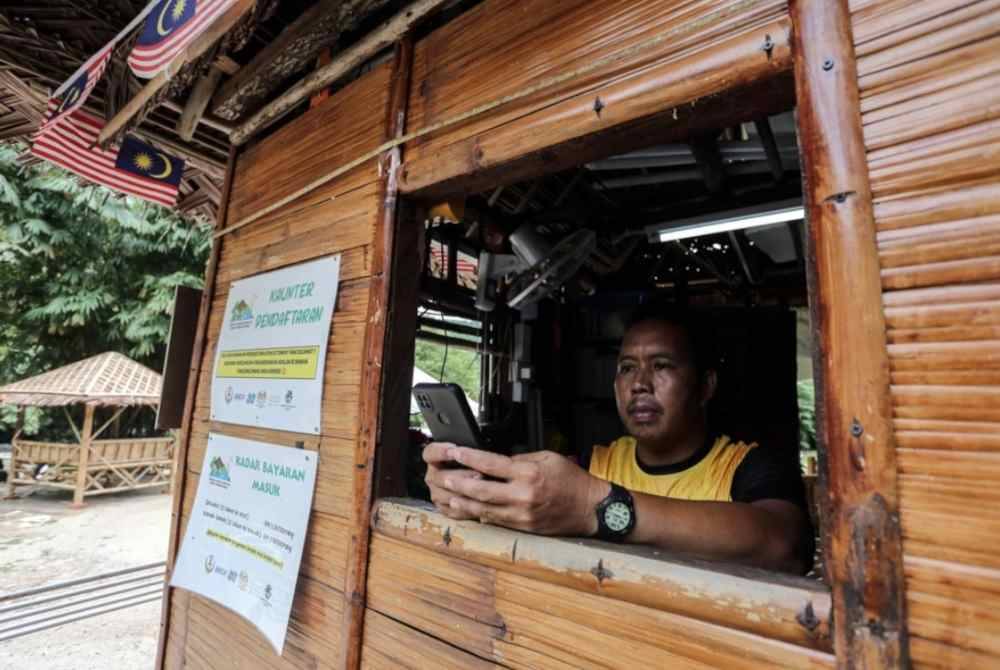 Che Wan menggunakan telefon bimbit di kaunter pendaftaran Kayuh D’Tonggang. Foto Bernama