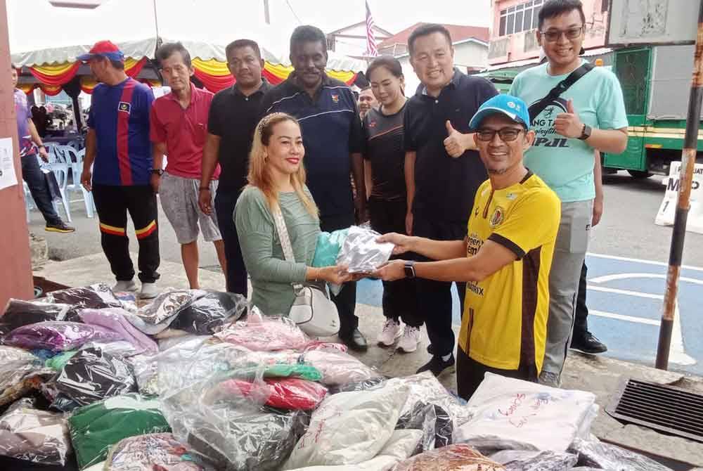 Mohd Nazri (kanan) ketika menyerahkan edaran pakaian terpakai kepada individu yang hadir pada program tersebut.
