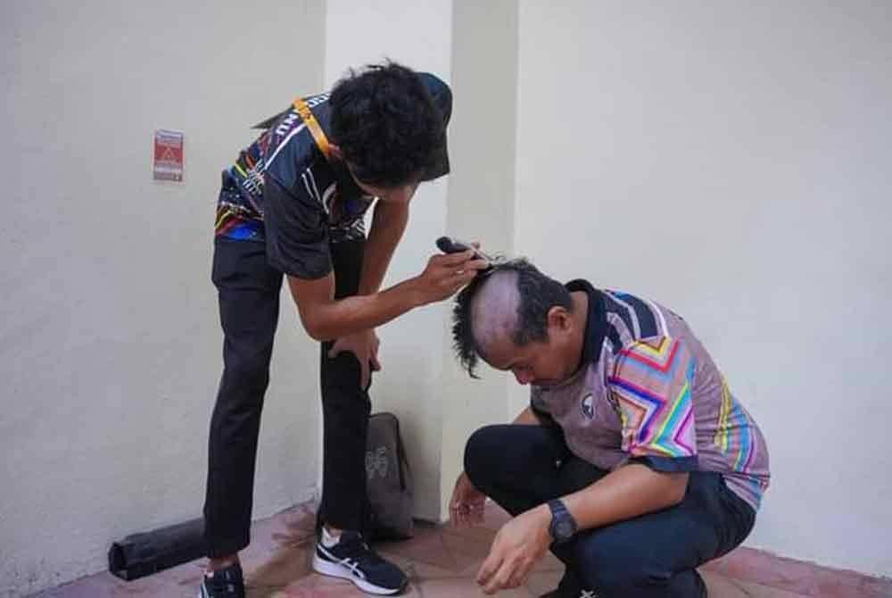Armin (kiri) memotong rambut Zainuddin. Foto FB Wan Sukairi Wan Abdullah.