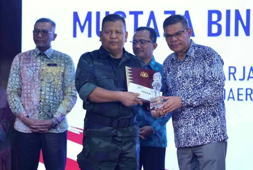 Saifuddin Nasution (kanan) menyampaikan hadiah tempat pertama kategori Lagu Patriotik kepada Mustaza Mustaffa (dua, kiri) pada Majlis Perhimpunan Bulanan KDN dan Sambutan Bulan Kebangsaan Tahun 2024 di Kompleks Setia Perkasa pada Khamis. Foto Bernama