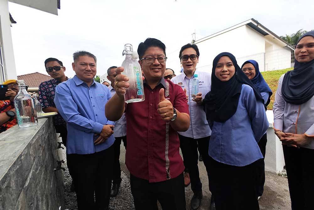 Ewon (tengah) menunjukkan air mineral beroksigen Bubbles O2 di Kampung Kanchong, Rantau pada Khamis. Turut kelihatan Arifin (kiri) dan Faizal (tiga dari kanan)