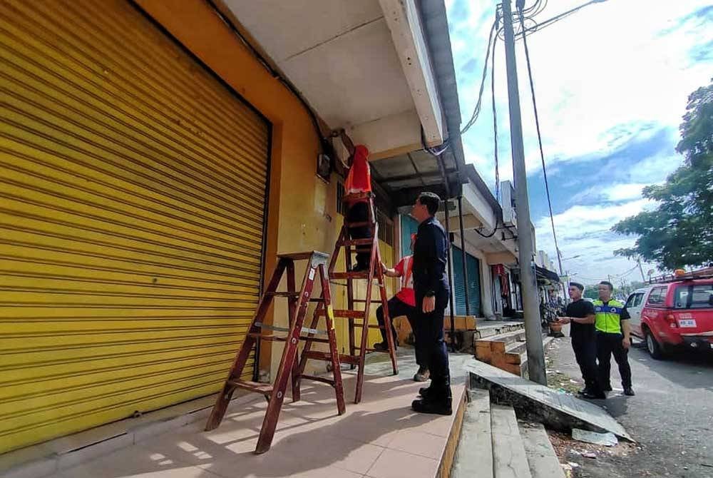 Azrul (dua dari kiri) ketika melihat kakitangan TNB melakukan kerja-kerja at pemotongan bekalan elektrik di Taman Sebang Mutiara pada Khamis.