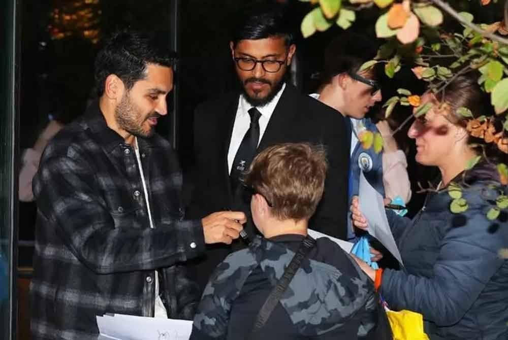Gundogan (kiri) melayan peminat City yang menunggunya di luar restoran Tast Catala milik Pep Guardiola. Foto: Agensi