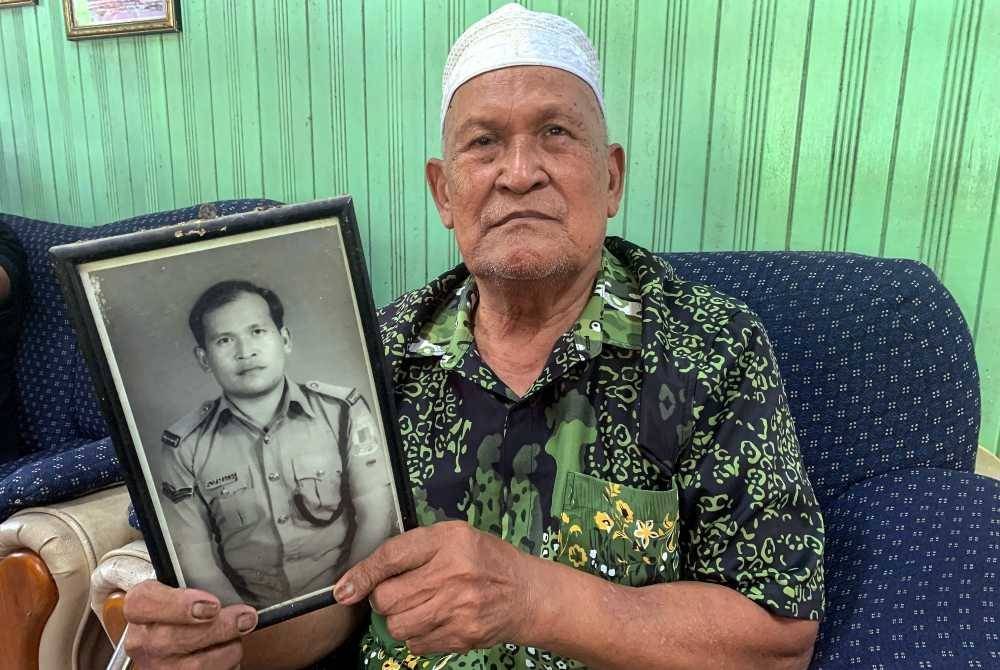 Hussin (tengah) menunjukkan gambarnya ketika bertugas sebagai polis ketika ditemui pemberita pada Program Santuni Pesara Polis Sempena Bulan Kemerdekaan IPD Bachok di Kampung Alor Bakat pada Khamis. Foto Bernama