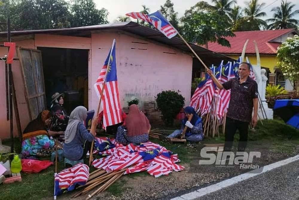 Penduduk bergotong-royong memasang bendera di laman rumah dan blok masing-masing.
