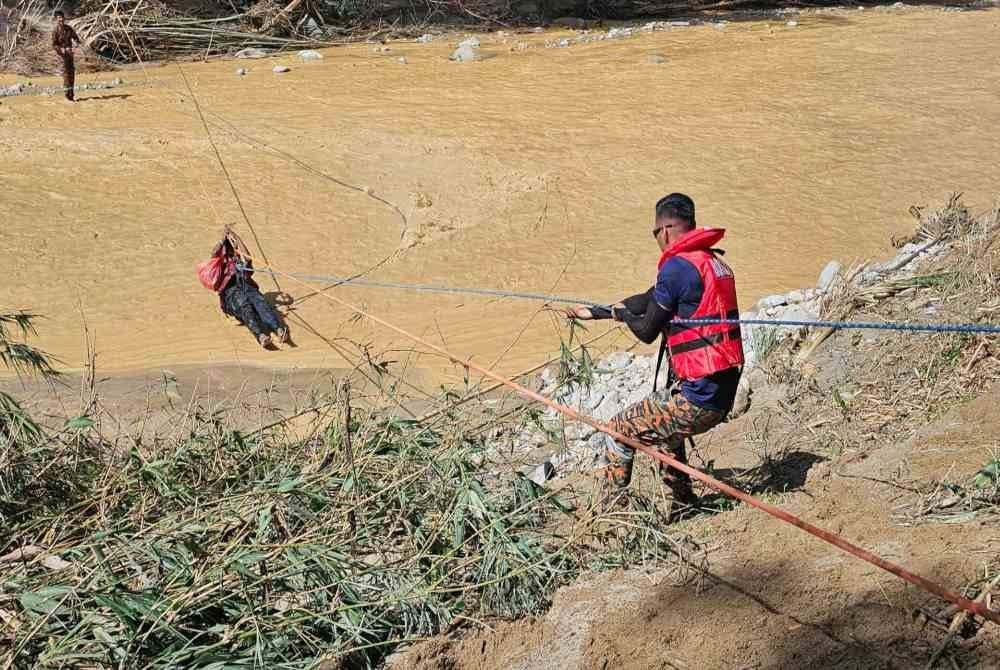 Seorang mangsa berjaya dibawa merentasi sungai selepas satu-satunya jambatan menghubung ke lokasi runtuh akibat kepala air.