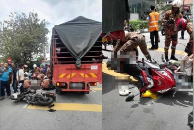 Anggota bomba mengeluarkan mayat mangsa yang tersepit di bawah tayar lori.