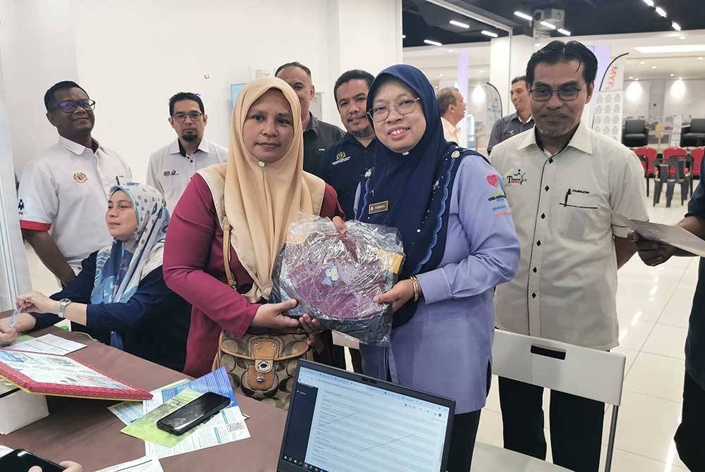Farihah (dua dari kanan) menyampaikan cenderamata kepada seorang peserta yang mengunjungi Karnival Kerjaya MyFutureJobs 'Tiada Yang Terpinggir' 2024 di KTCC Mall, Kuala Terengganu pada Ahad.