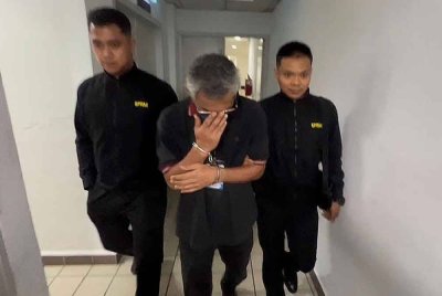 Tertuduh (tengah) ketika dihadapkan di Mahkamah Sesyen Kuala Terengganu pada Ahad.