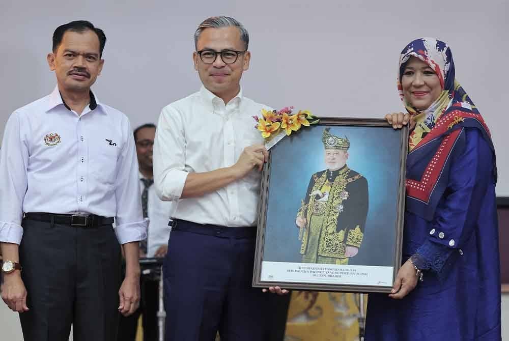 Fahmi (tengah) menyerahkan gambar potret Yang di-Pertuan Agong Sultan Ibrahim kepada Pengetua Sekolah Menengah Kebangsaan (SMK) Seri Pantai Sharin Hanum Ab Rahman (kanan) sempena Program Pentarama Kelab Malaysiaku di SMK Seri Pantai hari ini. - Foto: Bernama