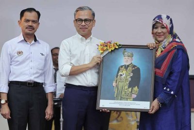 Fahmi (tengah) menyerahkan gambar potret Yang di-Pertuan Agong Sultan Ibrahim kepada Pengetua Sekolah Menengah Kebangsaan (SMK) Seri Pantai Sharin Hanum Ab Rahman (kanan) sempena Program Pentarama Kelab Malaysiaku di SMK Seri Pantai hari ini. - Foto: Bernama