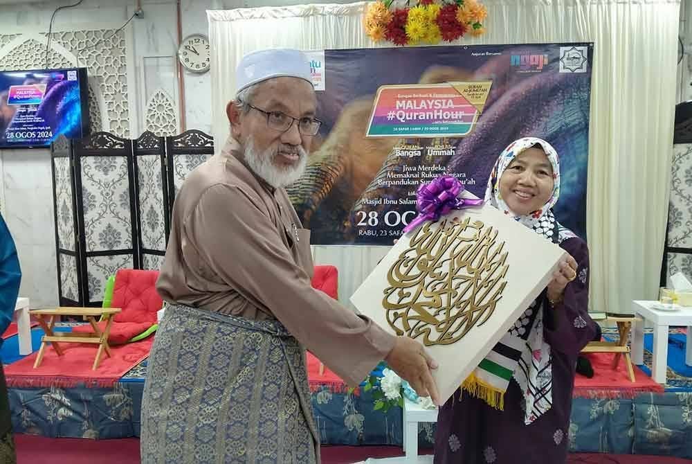 Robaatun Hadayiah menyampaikan cenderahati kepada Ahmad Husni selepas menyempurnakan perasmian Program Malaysia #QuranHour Peringkat Negeri Perak di Majid Ibnu Salam, Pengkalan Pegoh di sini pada Rabu.