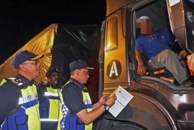 Stiem Van Lutam (tengah) memeriksa dokumen perjalanan dalam Ops Kenderaan Perdagangan di Plaza Tol Jitra, arah Selatan, malam tadi. Foto Bernama