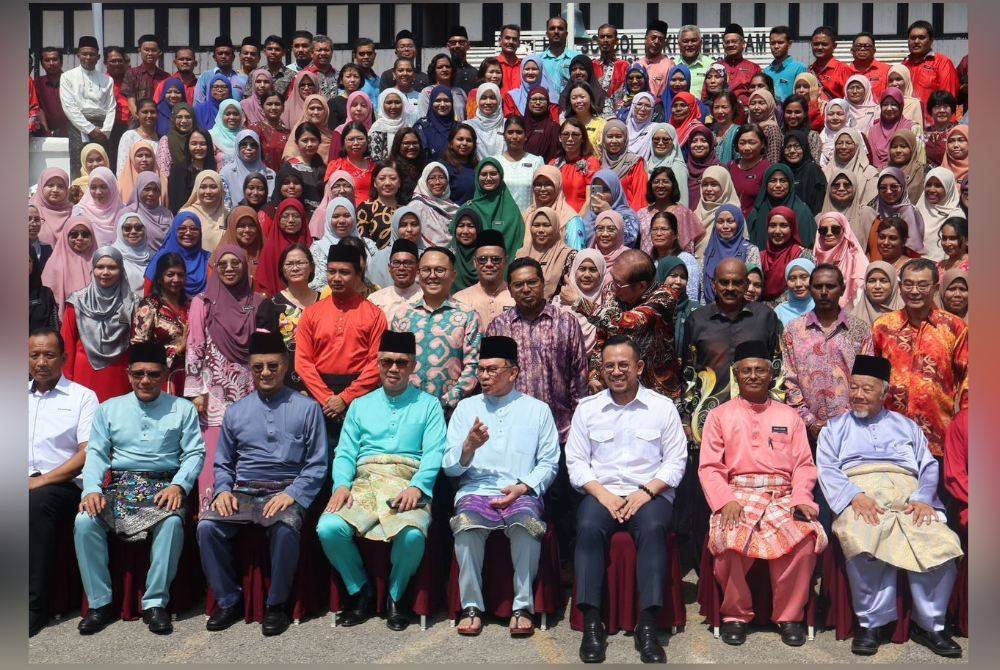 Anwar (duduk, empat dari kanan) bergambar bersama warga SMK Tinggi Bukit Mertajam.