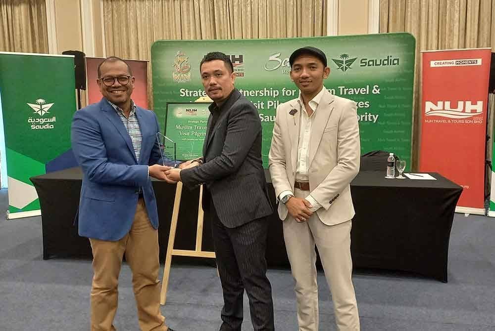 Abdul Halim Aliumar ( dua kanan) menyampaikan cederahati kepada Azman Ahmad (kiri) pada Majlis Menandatangani Rakan Strategik Kembara Muslim dan Pakej Umrah Ziarah Dubai di sebuah hotel di Petaling Jaya pada Khamis.