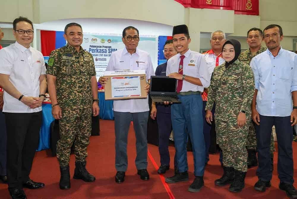 Mohamed Khalid (tiga, kiri) menyampaikan sumbangan Chrome Book kepada Ahmad Musyrif Nasiruddin Ahmad Musa (depan, tiga, kanan). Foto Bernama