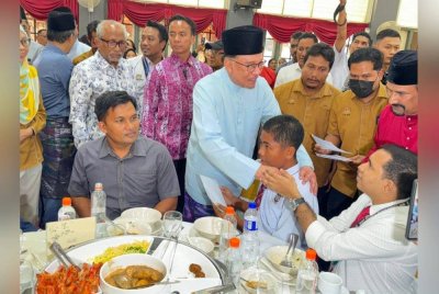 Anwar (tengah) beramah mesra dengan salah seorang pelajar SMK Tinggi Bukit Mertajam pada Jumaat.