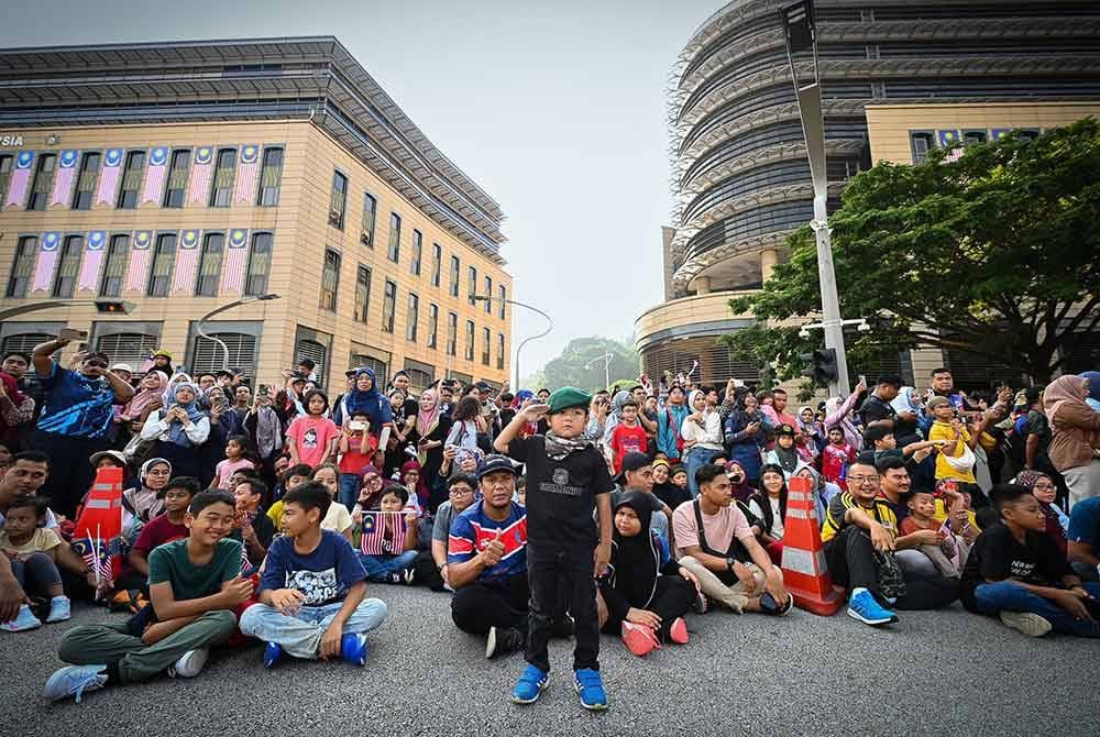 Telatah salah seorang penonton cilik yang memberikan tabik hormat kepada peserta perarakan sepanjang acara sambutan Hari Kebangsaan 2024