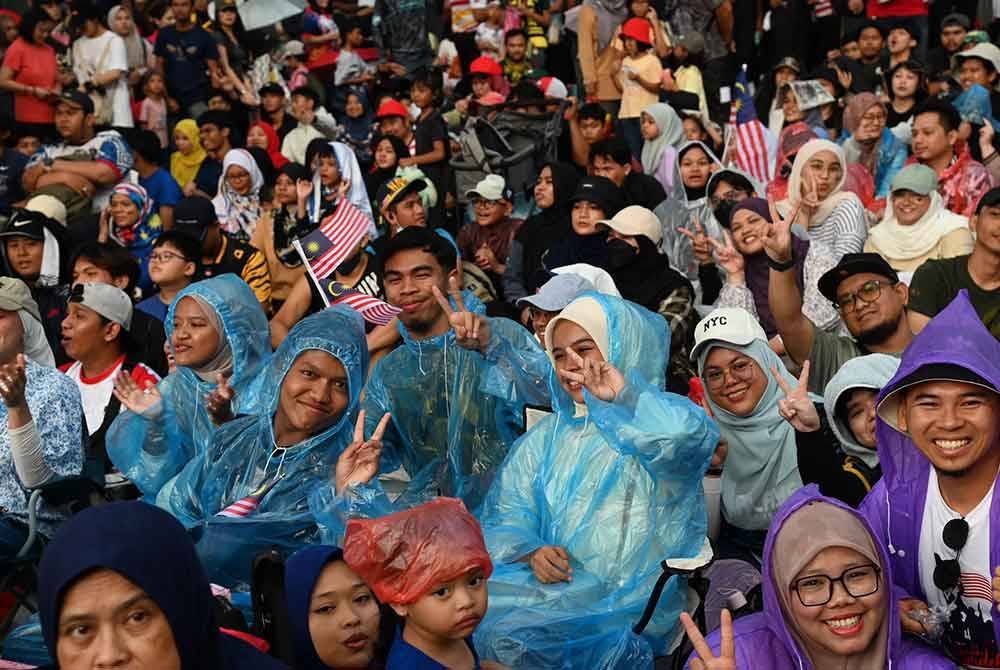 Walaupun hujan membasahi bumi seketika pada awal pagi, namun ia tidak mematahkan semangat dan keterujaan penonton yang hadir untuk melihat perarakan penuh. FOTO: Jabatan Penerangan Malaysia