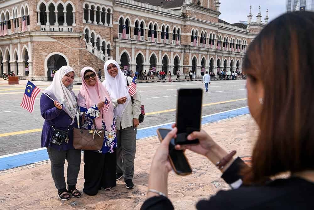 Peguam, Paizah Abdul Hamid, 62 (kanan) bersama ahli keluarganya menyambut Hari Kebangsaan ke-67 ketika tinjauan di Dataran Merdeka, pada Sabtu. Foto Bernama