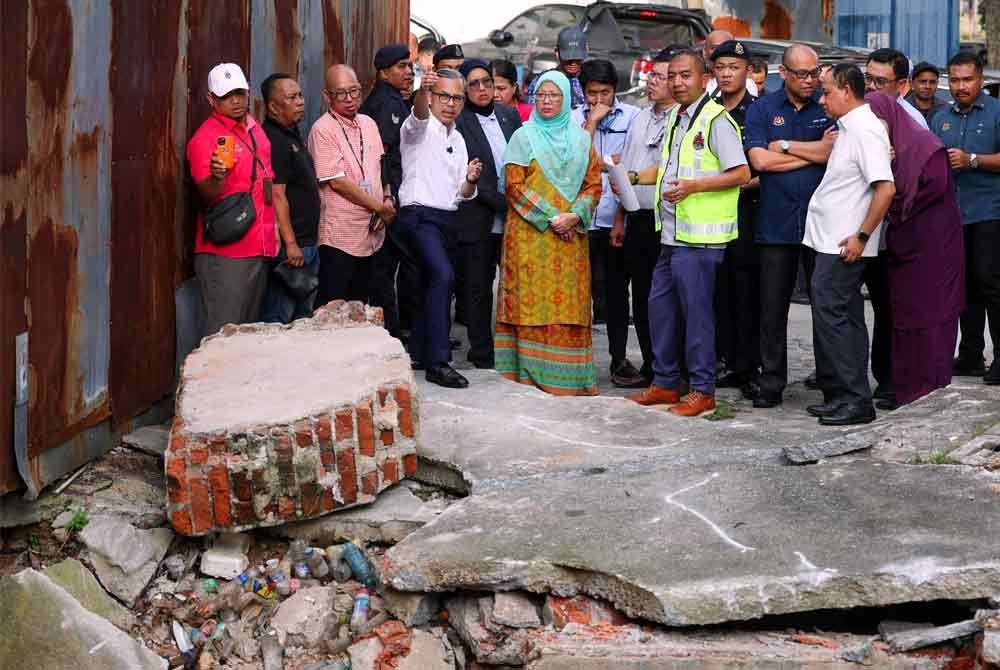 Dr Zaliha (lima, kanan) ketika meninjau keadaan mendapan tanah yang berlaku di Jalan Pantai Permai, Kampung Kerinchi. Foto Bernama 