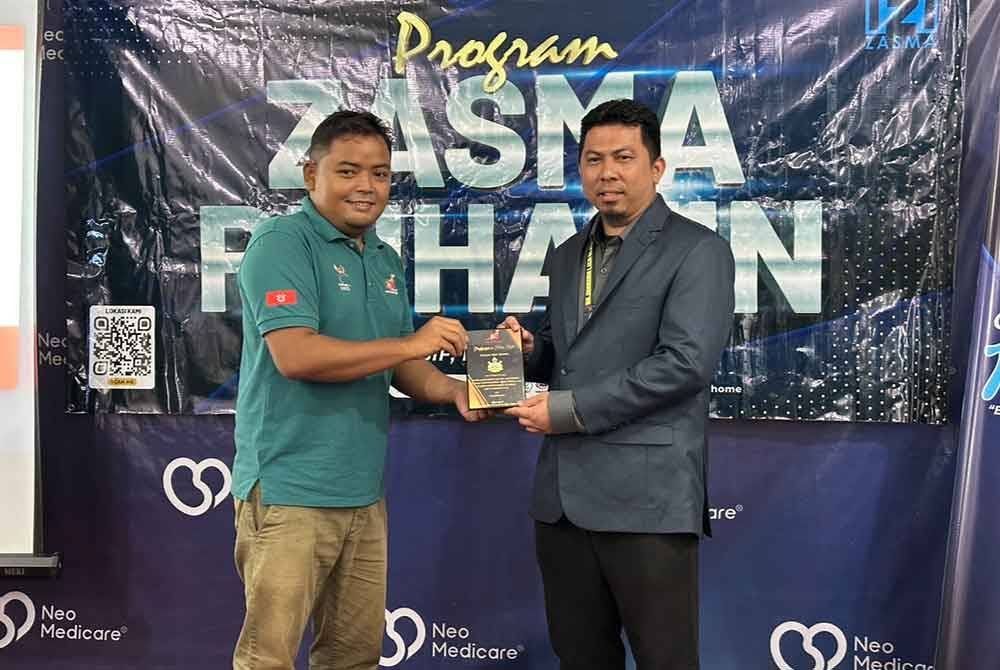 Mohd Firdaus (kanan) menerima cenderamata yang disampaikan Saiful Helmie (kiri) pada Majlis Penyerahan Jersi Rasmi kepada Pasukan Futsal Orang Pekak, di Kubang Kerian, Kota Bharu.