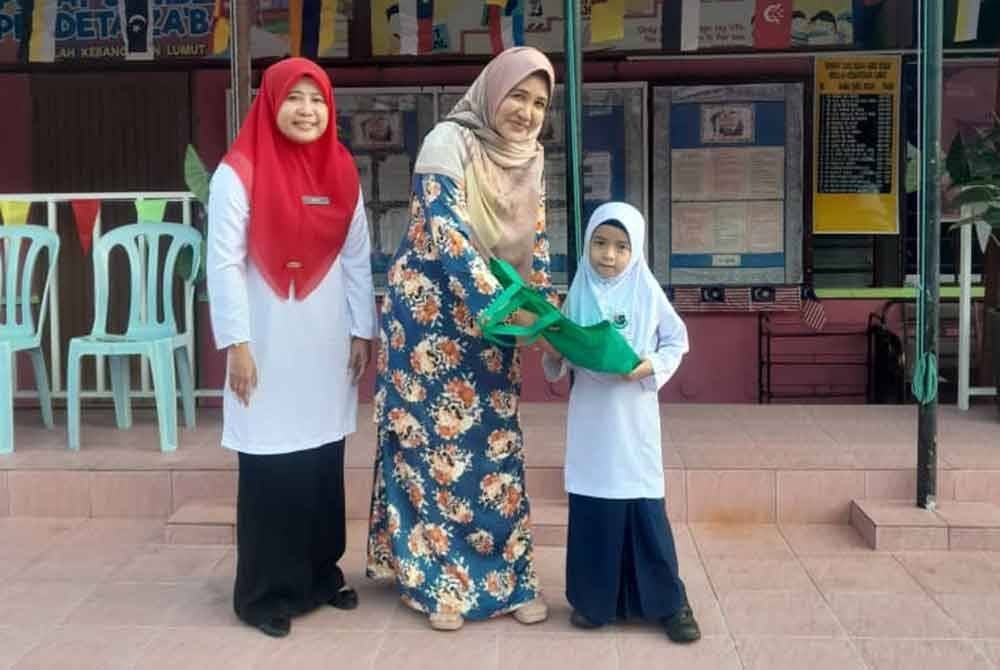 Maziah (tengah) menyampaikan naskhah al-Quran kepada Nur Aeera Afia yang berjaya mendapat tempat ketiga dalam pertandingan menghafal sempena Hari Kebangsaan ke-67 anjuran Rumah Ngaji Negeri Perak.