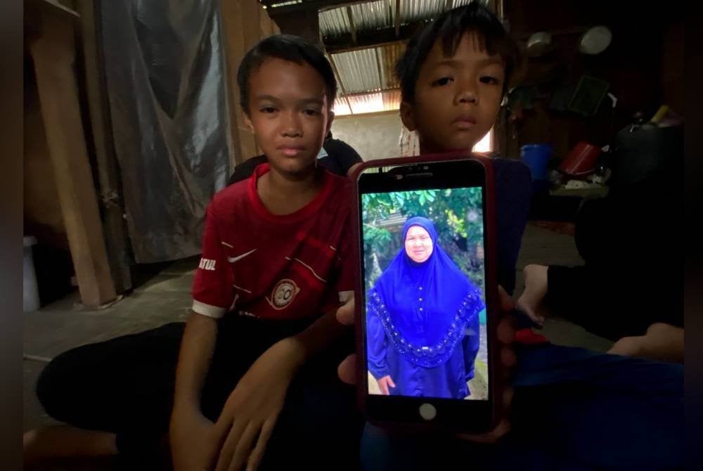 Dua beradik berusia 8 dan 12 tahun menunjukkan gambar ibu mereka.
