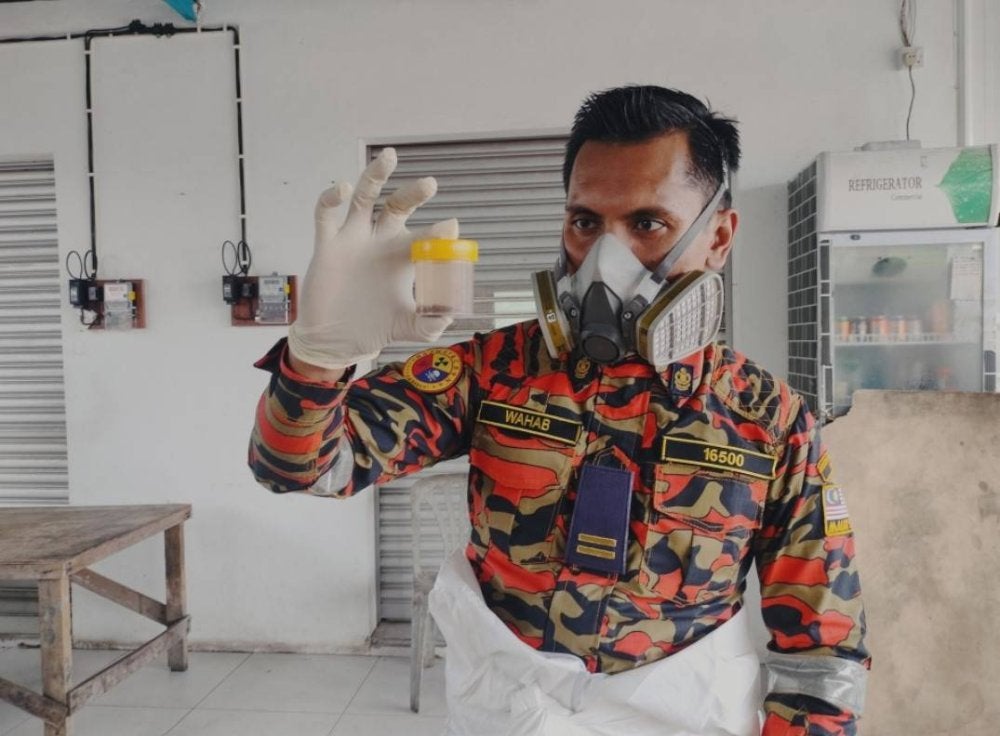 Anggota bomba menunjukkan sampel air yang diambil dari Sungai Pandan.