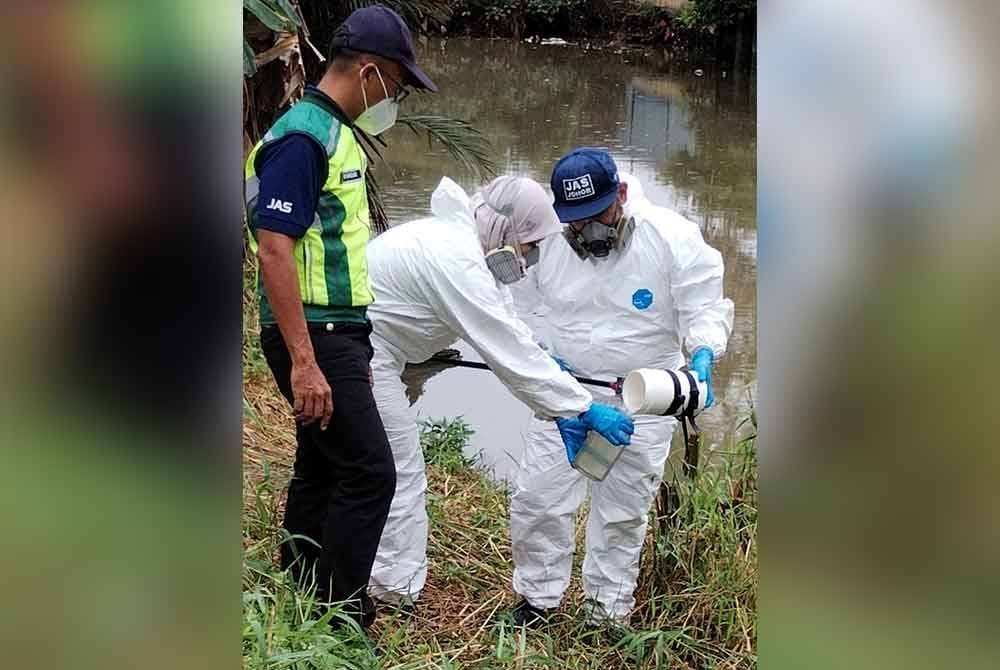Anggota Hazmat mengambil sampel air dari Sungai Pandan
