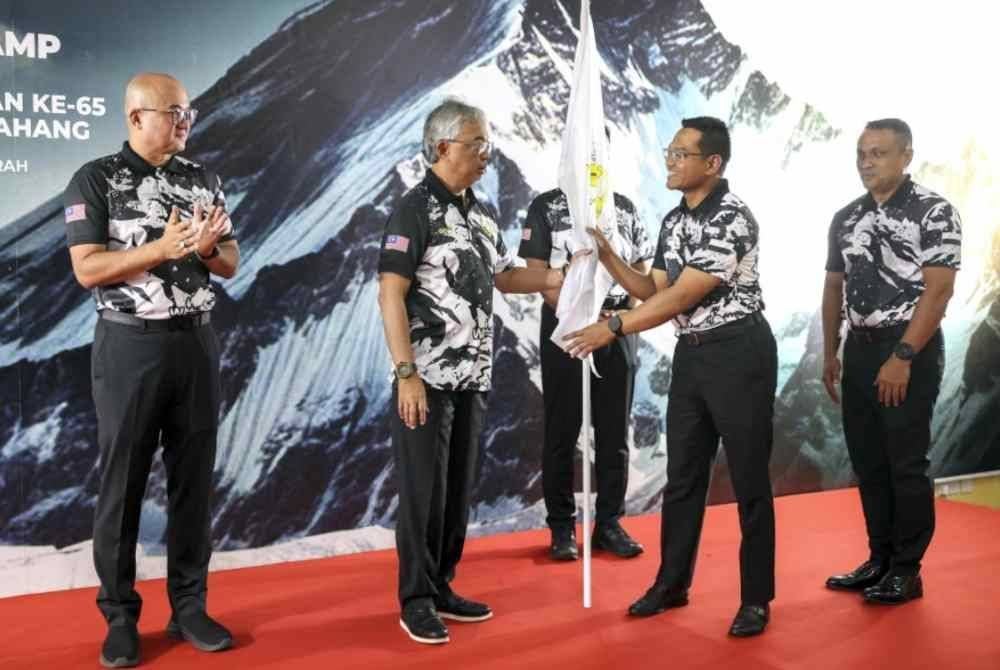 Sultan Pahang Al-Sultan Abdullah Ri'ayatuddin Al-Mustafa Billah Shah berkenan menyempurnakan penyerahan bendera ekspedisi kepada Pengelola Bijaya Diraja Sultan Pahang Datuk Ahmad Khirrizal Al Rahman (dua, kanan) pada Majlis Penyerahan Bendera Ekpedisi ke Everest Base Camp (EBC) sempena memuliakan Hari Ulang Tahun Keputeraan Ke-65 Sultan Pahang di Bukit Fraser hari ini. - Foto: Bernama