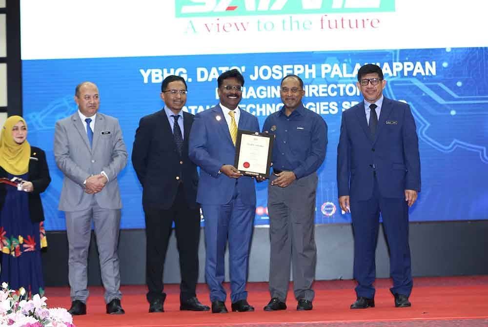 Zambry (dua dari kanan) menyampaikan watikah pelantikan CEO@POLYCC kepada Pengarah Urusan Satake Technologies Sdn Bhd, Datuk Joseph Palaniappan (tengah).