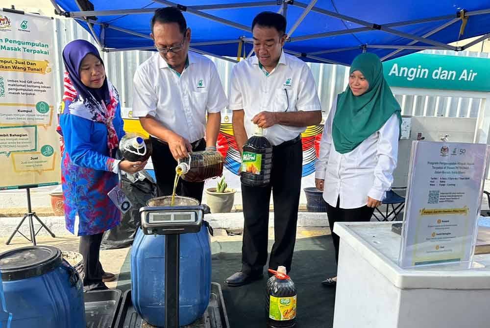 Mohamed Rafik (dua dari kiri) menuang minyak masak terpakai ke dalam tong untuk ditimbang dan dikitar semula.