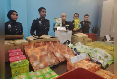 Ahmad Sukarno (tengah) menunjukkan antara bungkusan disyaki berisi dadah yang dirampas polis dalam serbuan pada 30 Ogos lalu.