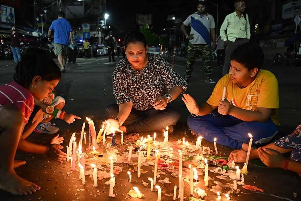 Peserta protes menyalakan lilin sebagai simbol membantah pemerkosaan dan pembunuhan seorang doktor pelatih pada bulan lalu.