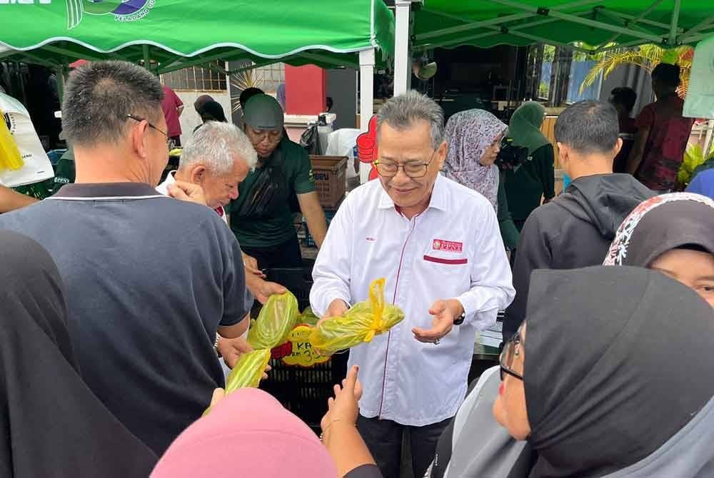 Mohd Rosli (tengah) menyantuni pengunjung sempena pelancaran Pasar Peladang Outlet Terengganu (POT) di pekarangan Wisma Peladang, Kuala Terengganu pada Jumaat.
