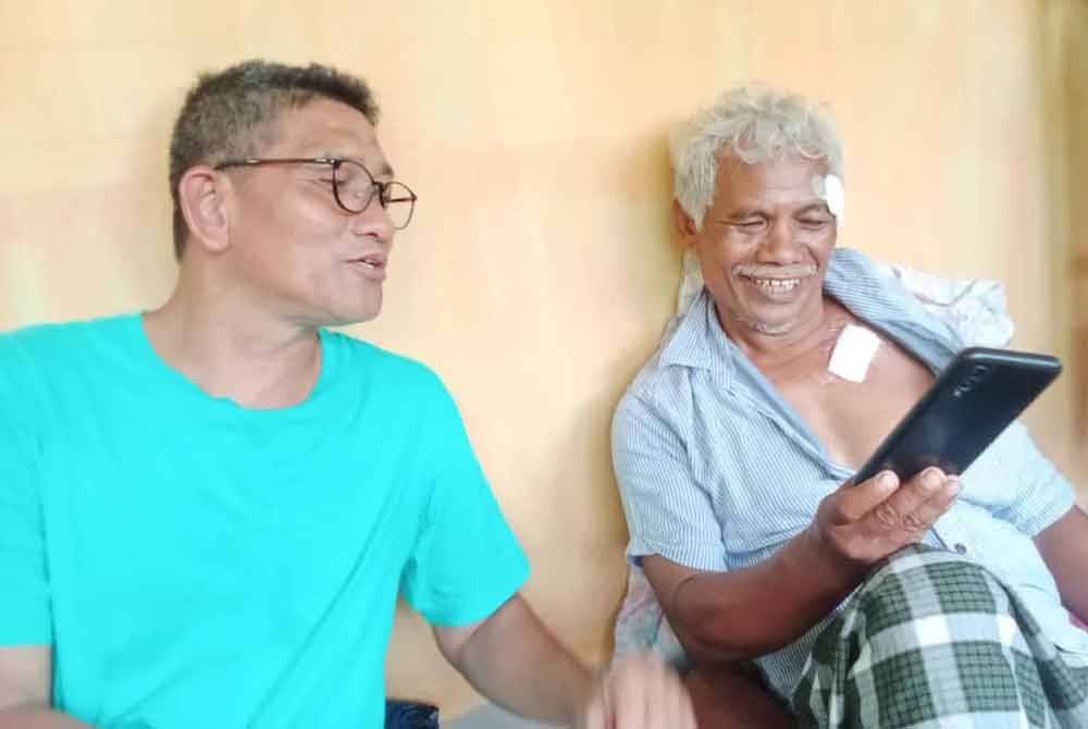 Tok Atan (kiri) menunjukkan gambar Arshad sewaktu kejadian.