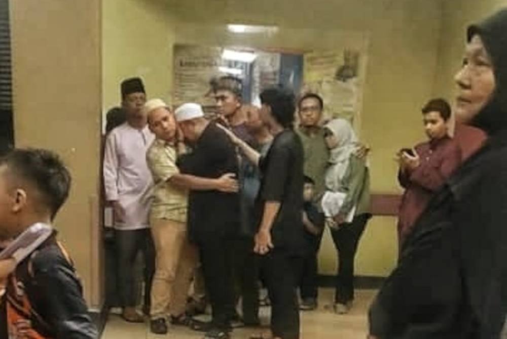 Mohd Fikry Amri (tengah) tidak dapat menahan sebak selepas keluar dari bilik Unit Forensik Alor Gajah pada Jumaat.